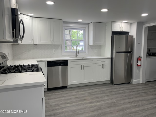 219 Hyers St, Toms River, NJ 08753 - kitchen featuring appliances with stainless steel finishes, a sink, washer / clothes dryer, decorative backsplash, and white cabinetry