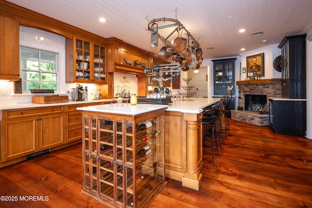 1 Beechwood Ter, Matawan, NJ 07747 - kitchen featuring recessed lighting, a brick fireplace, brown cabinets, dark wood finished floors, and a kitchen bar