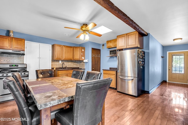 2419 Mallow St, Point Pleasant, NJ 08742 - kitchen with appliances with stainless steel finishes, under cabinet range hood, tasteful backsplash, a ceiling fan, and a kitchen breakfast bar