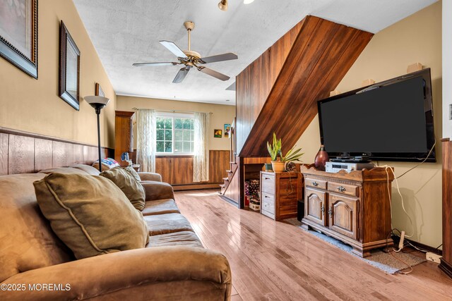 2419 Mallow St, Point Pleasant, NJ 08742 - living area featuring light wood finished floors, a baseboard heating unit, ceiling fan, wainscoting, and stairway