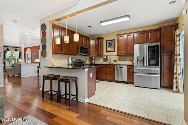 2420 Canterbury Ln, North Brunswick, NJ 08902 - kitchen featuring stainless steel appliances, a peninsula, a kitchen breakfast bar, decorative backsplash, and hanging light fixtures