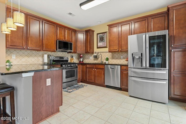 2420 Canterbury Ln, North Brunswick, NJ 08902 - kitchen featuring stainless steel appliances, light tile patterned flooring, decorative backsplash, a kitchen bar, and pendant lighting