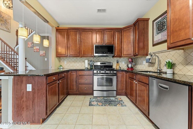 2420 Canterbury Ln, North Brunswick, NJ 08902 - kitchen with appliances with stainless steel finishes, a sink, a peninsula, dark stone counters, and light tile patterned flooring