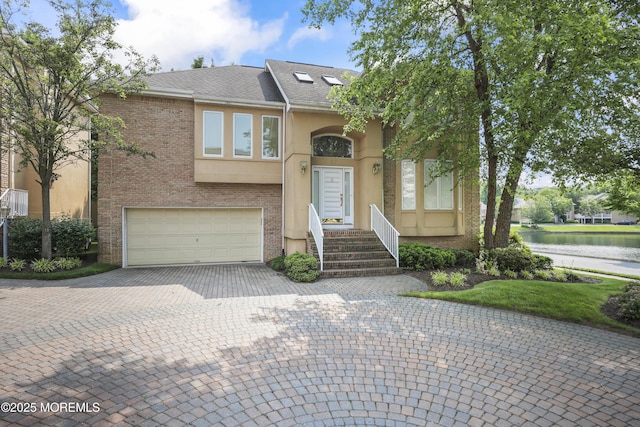 117 Sequoia Woods Ct, Holmdel, NJ 07733 - view of front of house with a garage, a water view, driveway, stucco siding, and brick siding