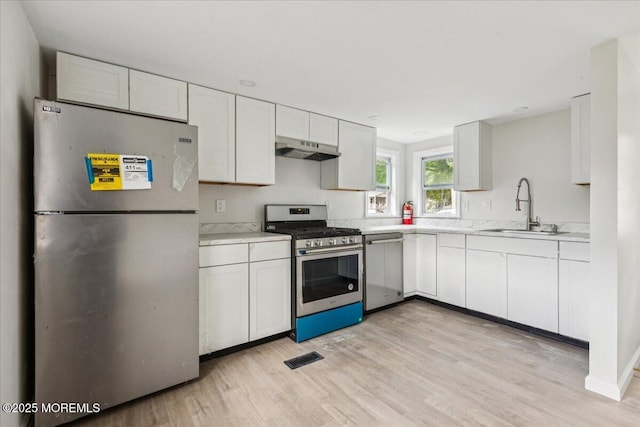 46 Roberts Rd, Toms River, NJ 08755 - kitchen featuring appliances with stainless steel finishes, a sink, under cabinet range hood, light wood-style floors, and white cabinetry