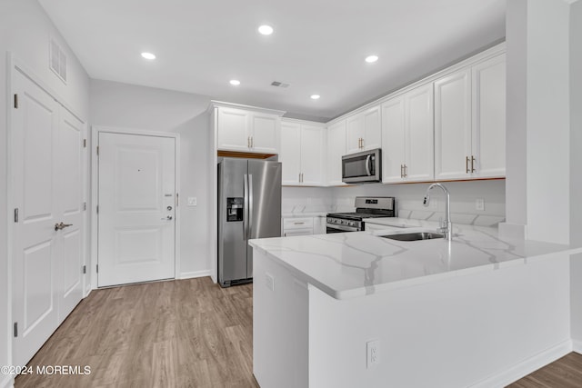 750 Lighthouse Dr Unit 1112, Barnegat, NJ 08005 - kitchen featuring stainless steel appliances, a sink, light stone counters, a peninsula, and light wood-type flooring