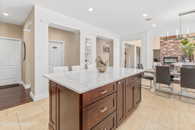 806 Turquoise Trl, Morganville, NJ 07751 - kitchen featuring a fireplace, a kitchen island, light stone counters, pendant lighting, and light tile patterned floors