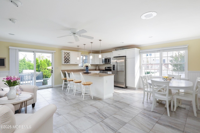 3 Watson Pl, Manasquan, NJ 08736 - kitchen featuring stainless steel appliances, crown molding, a peninsula, wainscoting, and a kitchen bar