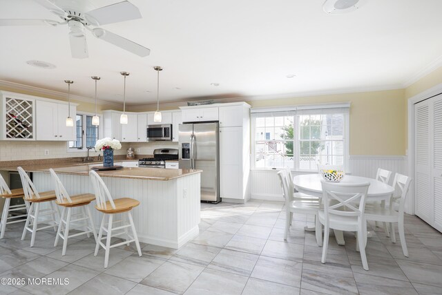 3 Watson Pl, Manasquan, NJ 08736 - kitchen with appliances with stainless steel finishes, plenty of natural light, ornamental molding, a breakfast bar area, and white cabinetry