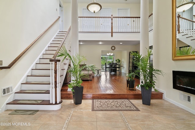 323 Florence Ave, Long Branch, NJ 07740 - foyer entrance featuring stairs, baseboards, a towering ceiling, a glass covered fireplace, and a chandelier