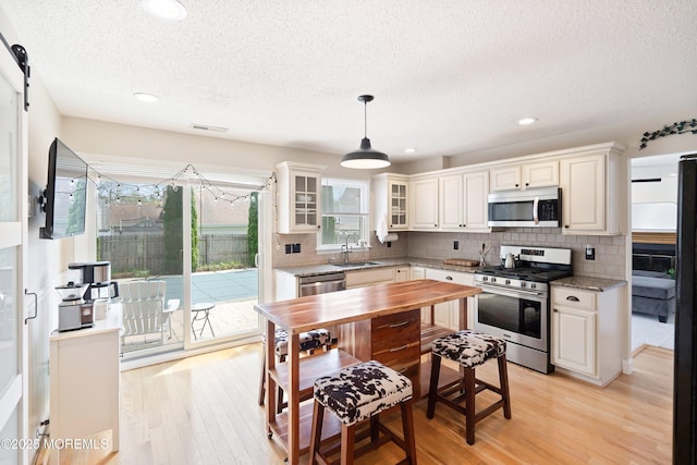 15 Tanglewood Dr, Barnegat, NJ 08005 - kitchen with stainless steel appliances, a textured ceiling, decorative backsplash, light wood-type flooring, and glass insert cabinets