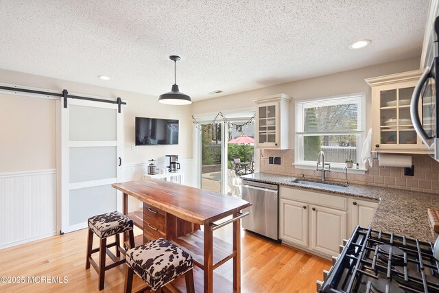 15 Tanglewood Dr, Barnegat, NJ 08005 - kitchen with stainless steel dishwasher, a textured ceiling, a barn door, light wood finished floors, and a wainscoted wall