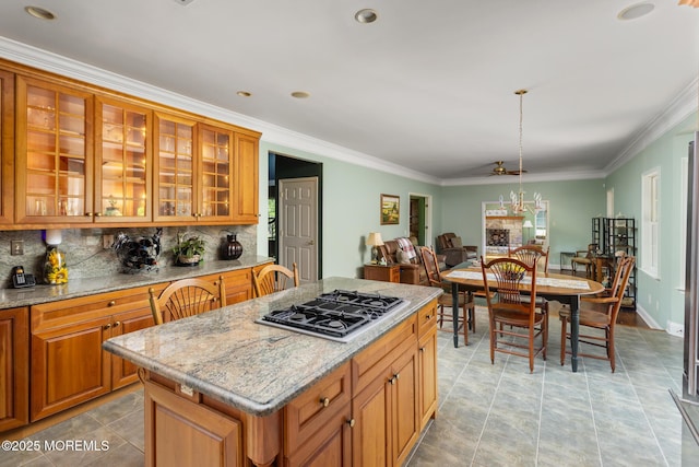 1 Yeger Dr, Upper Freehold, NJ 08501 - kitchen featuring stainless steel gas stovetop, tasteful backsplash, crown molding, a kitchen island, and brown cabinets