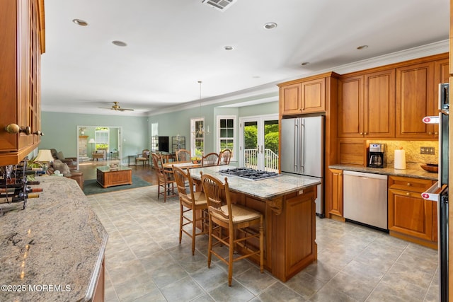 1 Yeger Dr, Upper Freehold, NJ 08501 - kitchen with stainless steel appliances, healthy amount of natural light, brown cabinetry, open floor plan, and crown molding