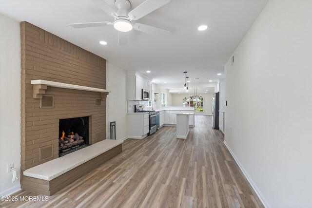 21 Turnbridge, Manchester, NJ 08759 - unfurnished living room featuring light wood-style floors, a brick fireplace, baseboards, ceiling fan, and recessed lighting