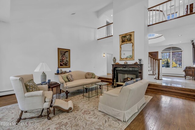 34 Bruns Rd, West Allenhurst, NJ 07711 - living area with hardwood / wood-style floors, a towering ceiling, a fireplace, a baseboard radiator, and stairs