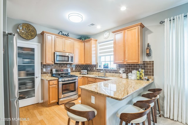 85 Briarwood Dr, Little Egg Harbor, NJ 08087 - kitchen with appliances with stainless steel finishes, a sink, a peninsula, a kitchen bar, and light stone countertops
