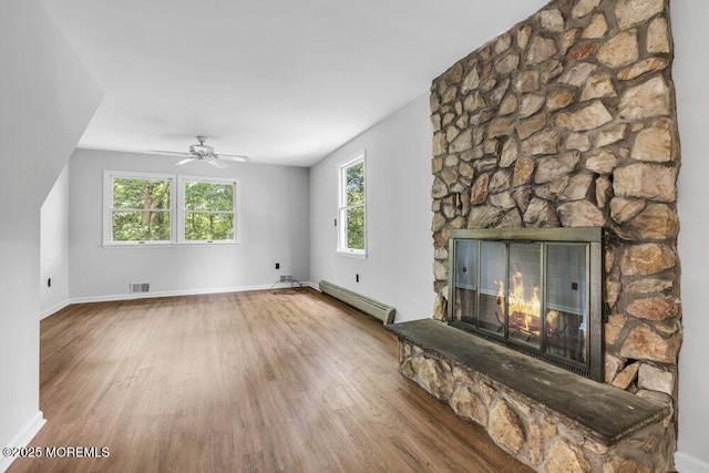 25 Overhill Rd, Ocean Twp, NJ 07712 - unfurnished living room with baseboard heating, wood finished floors, a stone fireplace, and ceiling fan