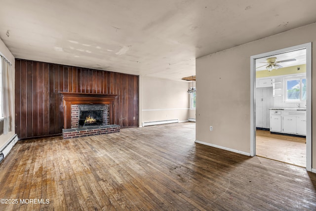 812 Donna Dr, Point Pleasant, NJ 08742 - unfurnished living room featuring baseboard heating, hardwood / wood-style flooring, a brick fireplace, and a ceiling fan