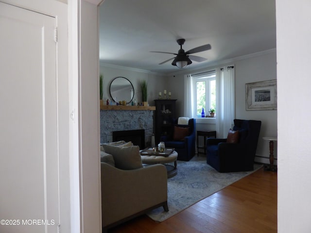 91 Center Ave, Atlantic Highlands, NJ 07716 - living area featuring wood finished floors, a ceiling fan, a baseboard radiator, a stone fireplace, and ornamental molding
