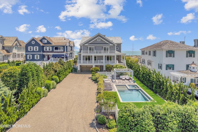 1055 Ocean Ave, Mantoloking, NJ 08738 - back of property with a balcony, a garage, a pool with connected hot tub, driveway, and a residential view