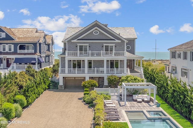 1055 Ocean Ave, Mantoloking, NJ 08738 - rear view of property featuring stairway, stone siding, a balcony, a garage, and a pool with connected hot tub