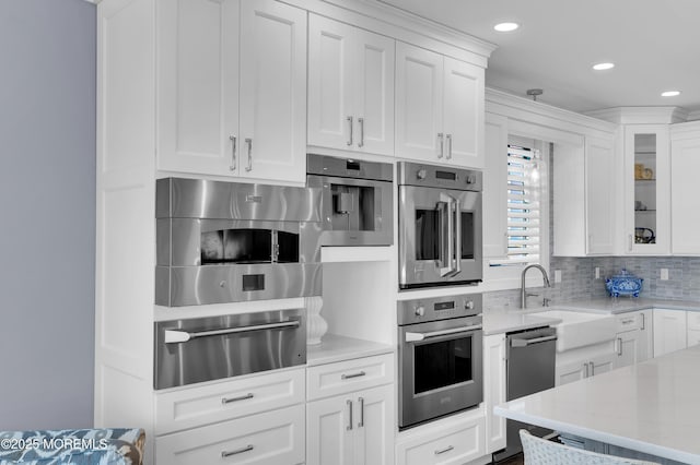 1055 Ocean Ave, Mantoloking, NJ 08738 - kitchen with a warming drawer, a sink, white cabinetry, stainless steel appliances, and backsplash