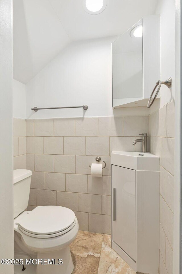29 Grand Ave, Atlantic Highlands, NJ 07716 - half bath featuring tile walls, toilet, vanity, lofted ceiling, and wainscoting