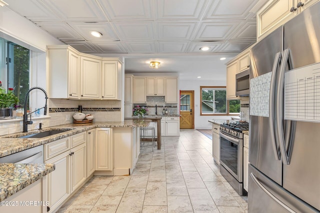 29 Grand Ave, Atlantic Highlands, NJ 07716 - kitchen with appliances with stainless steel finishes, cream cabinetry, a sink, tasteful backsplash, and light stone countertops