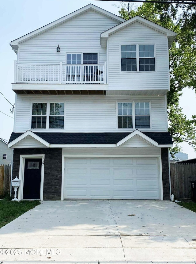 257 Port Monmouth Rd, Port Monmouth, NJ 07758 - view of front facade featuring a balcony, an attached garage, concrete driveway, and stone siding