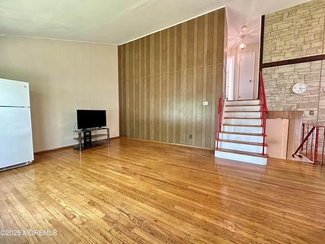 404 Harmony Rd, Middletown, NJ 07748 - unfurnished living room with hardwood / wood-style flooring, wood walls, and stairs