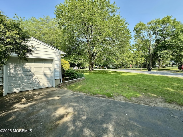 404 Harmony Rd, Middletown, NJ 07748 - view of grassy yard with an outdoor structure, asphalt driveway, a detached garage, and view of scattered trees