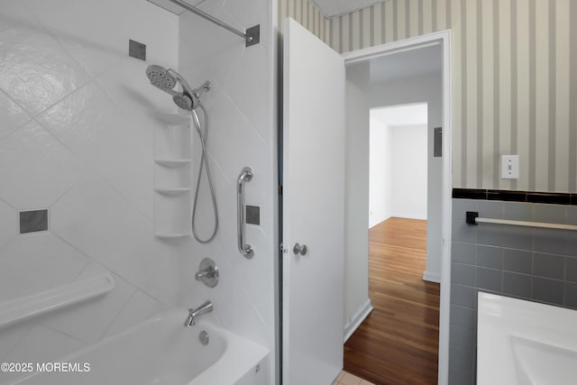 283 Spring St Unit 283B, Red Bank, NJ 07701 - bathroom featuring wallpapered walls, tub / shower combination, wood finished floors, tile walls, and wainscoting