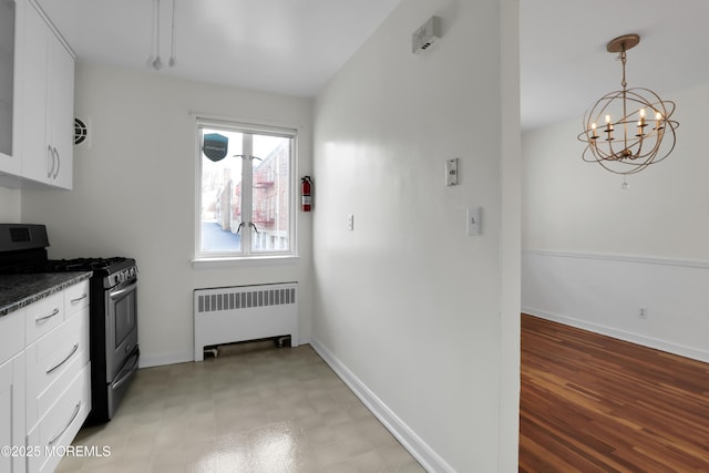 283 Spring St Unit 283B, Red Bank, NJ 07701 - kitchen with radiator heating unit, stainless steel gas range oven, dark countertops, white cabinetry, and a chandelier