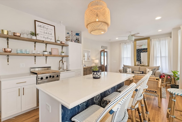 142 Heck Ave, Ocean Grove, NJ 07756 - kitchen featuring a sink, light wood-style floors, open shelves, white cabinetry, and a kitchen bar