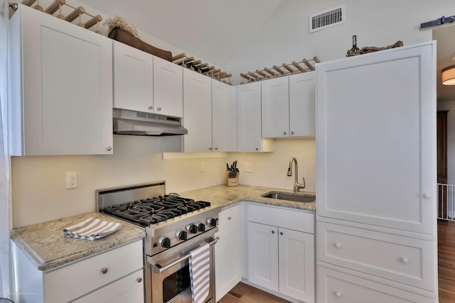 142 Heck Ave, Ocean Grove, NJ 07756 - kitchen with under cabinet range hood, high end stove, a sink, white cabinets, and light stone countertops