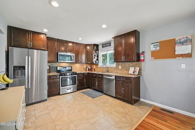 67 Koenig Ln, Freehold, NJ 07728 - kitchen featuring appliances with stainless steel finishes, decorative backsplash, open shelves, dark brown cabinets, and light stone countertops
