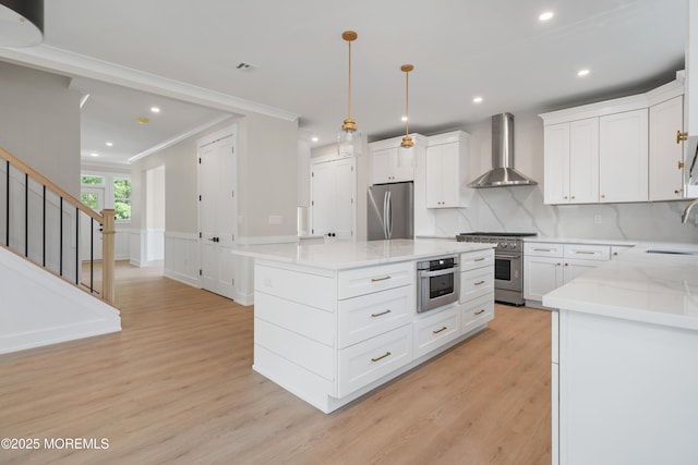 783 Delaware Ave, Manahawkin, NJ 08050 - kitchen featuring wall chimney range hood, stainless steel appliances, crown molding, a sink, and light wood-style flooring