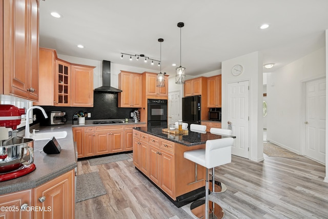 7 Cranberry Ct, Haledon, NJ 07508 - kitchen featuring wall chimney exhaust hood, black appliances, a breakfast bar, light wood-style floors, and a kitchen island