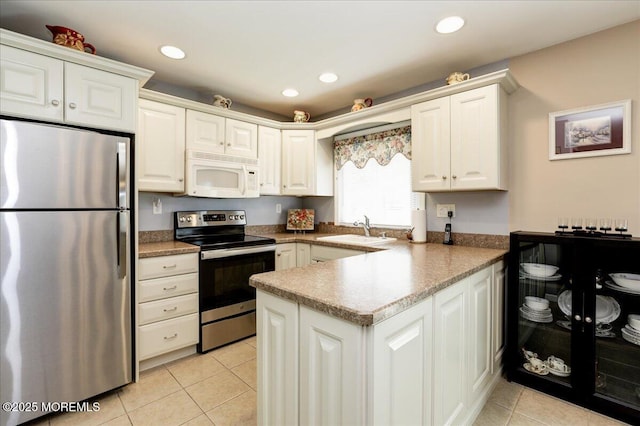 648 Pulham Ct Unit B, Manchester, NJ 08759 - kitchen featuring appliances with stainless steel finishes, a sink, a peninsula, light tile patterned flooring, and white cabinetry