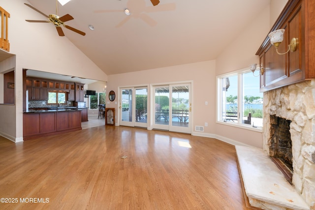 324 Magnolia Ave, Brielle, NJ 08730 - unfurnished living room featuring high vaulted ceiling, a ceiling fan, a stone fireplace, and light wood-style floors
