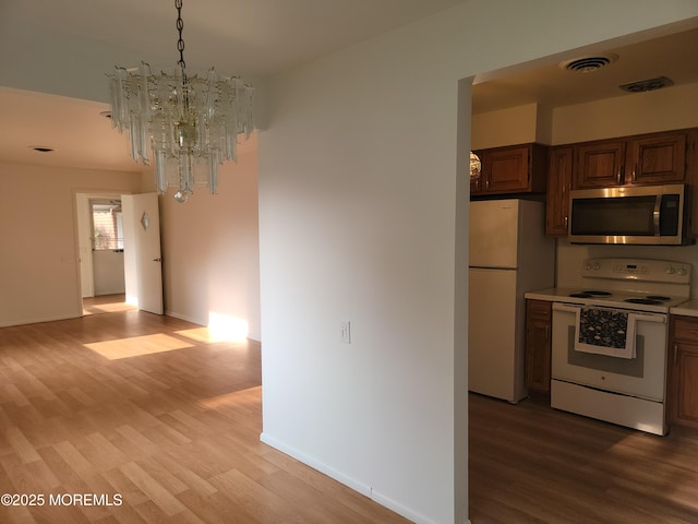 799 Hudson Pkwy, Whiting, NJ 08759 - kitchen with white appliances, light wood-style flooring, a chandelier, light countertops, and baseboards