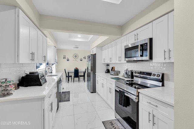 404B Newport Way, Monroe, NJ 08831 - kitchen featuring appliances with stainless steel finishes, a raised ceiling, white cabinetry, light marble finish floors, and decorative backsplash