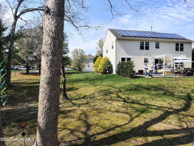 18 Mount Ranier Dr, Howell, NJ 07731 - rear view of house with roof mounted solar panels, a pergola, a lawn, and a patio