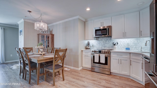 33 Sumner Ave Unit 1A, Seaside Heights, NJ 08751 - kitchen featuring appliances with stainless steel finishes, a chandelier, crown molding, white cabinetry, and tasteful backsplash