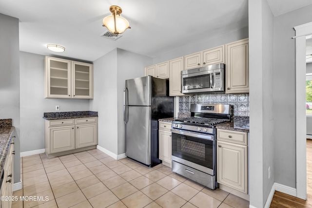 55 S Ave, Bayville, NJ 08721 - kitchen featuring stainless steel appliances, cream cabinets, baseboards, decorative backsplash, and glass insert cabinets