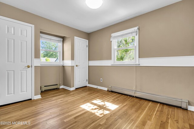 55 S Ave, Bayville, NJ 08721 - unfurnished bedroom featuring baseboard heating, a baseboard radiator, multiple windows, and light wood-style floors