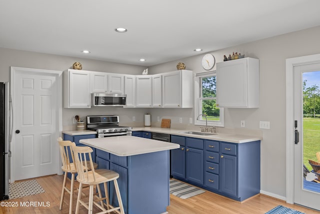 69 Eayrestown Rd, Medford, NJ 08055 - kitchen with stainless steel appliances, blue cabinetry, a sink, a kitchen bar, and light wood-style floors