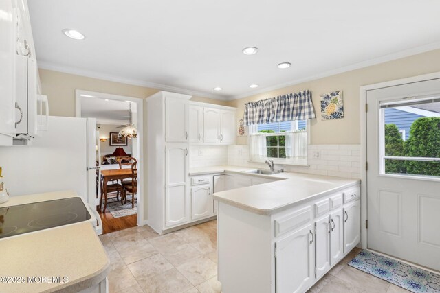 10 Weybridge Pl, Manchester, NJ 08759 - kitchen featuring a sink, a peninsula, crown molding, tasteful backsplash, and white cabinetry
