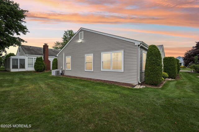 10 Weybridge Pl, Manchester, NJ 08759 - back of house at dusk with a lawn, a cooling unit, and a sunroom